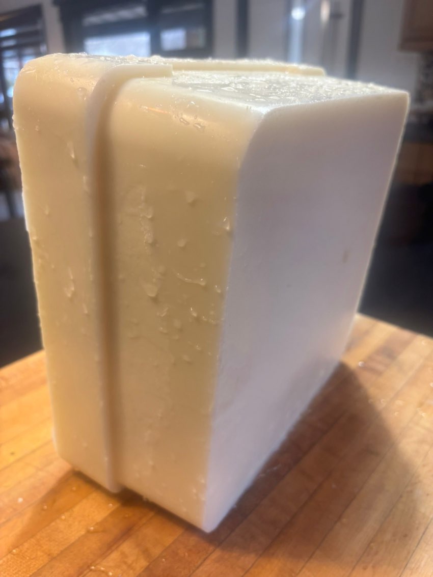 A block of rendered grass-fed tallow on a wooden board